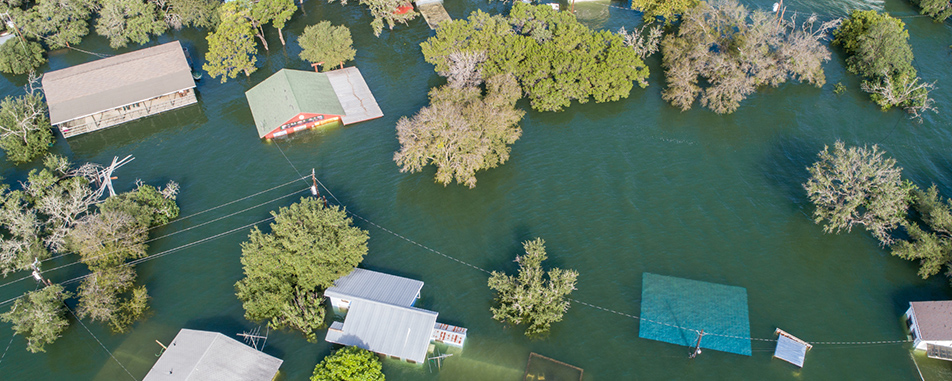Aerial view of a residential area flooded with water, showing partially submerged houses and trees. Aerial view of a residential area flooded with water, showing partially submerged houses and trees.